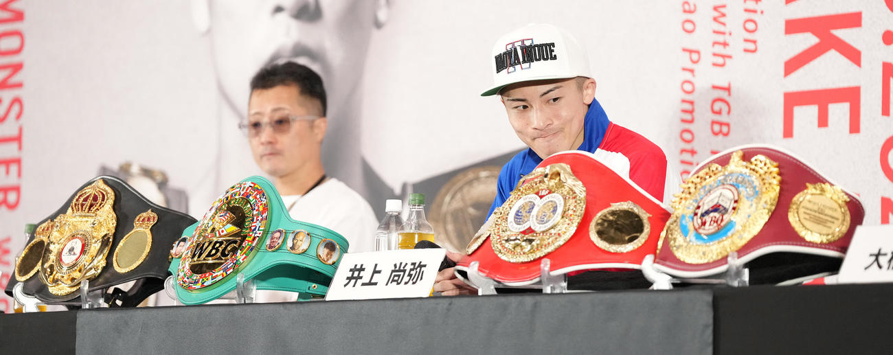 4団体王座統一した井上尚は会見でベルトを見る。左は父真吾トレーナー（撮影・鈴木みどり）