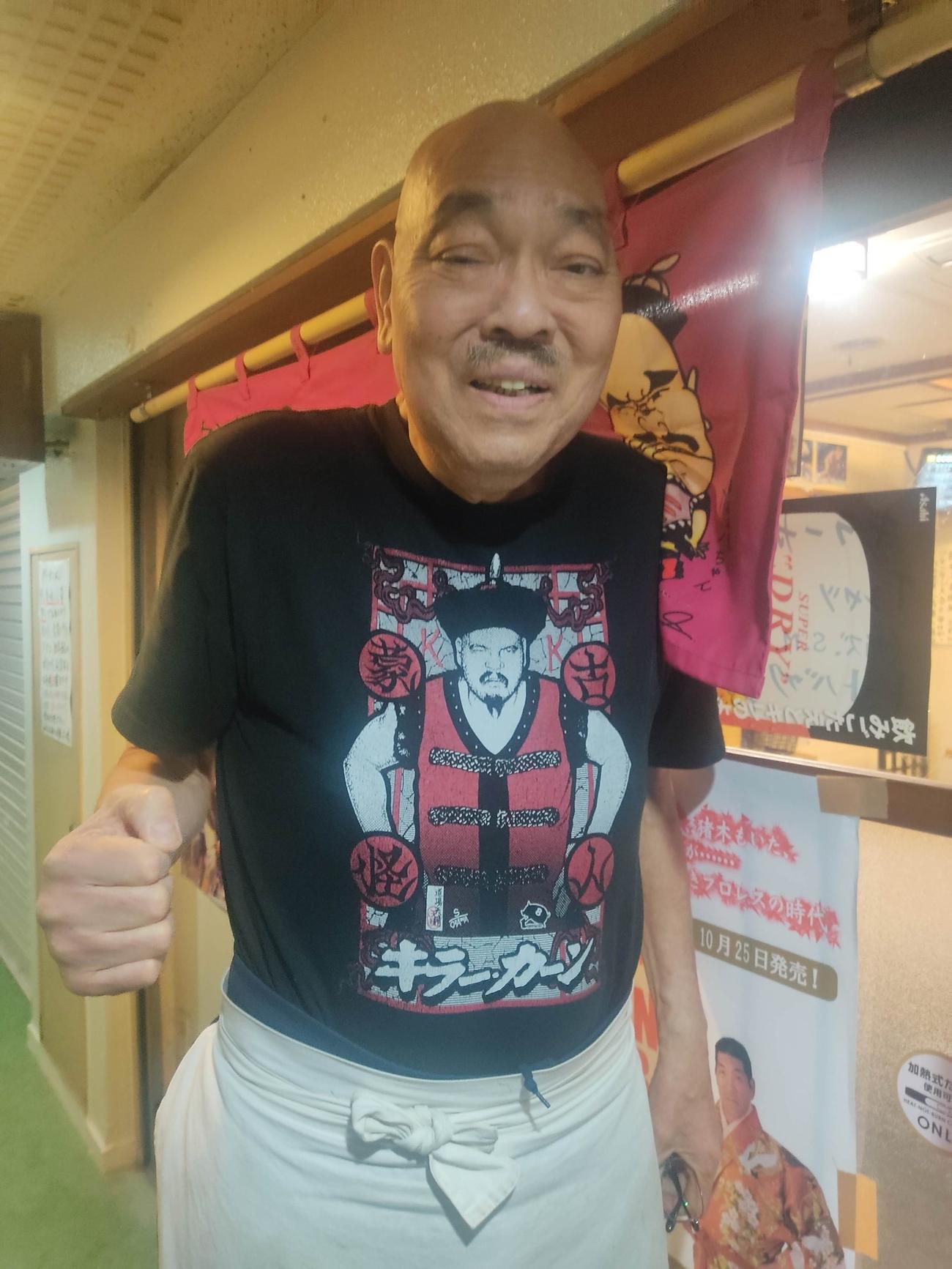 亡くなる5時間前、のれんをかけた前で右拳を握ったキラー・カーンさん（キラーカンの店　カンちゃんの人情酒場の公式Xから）