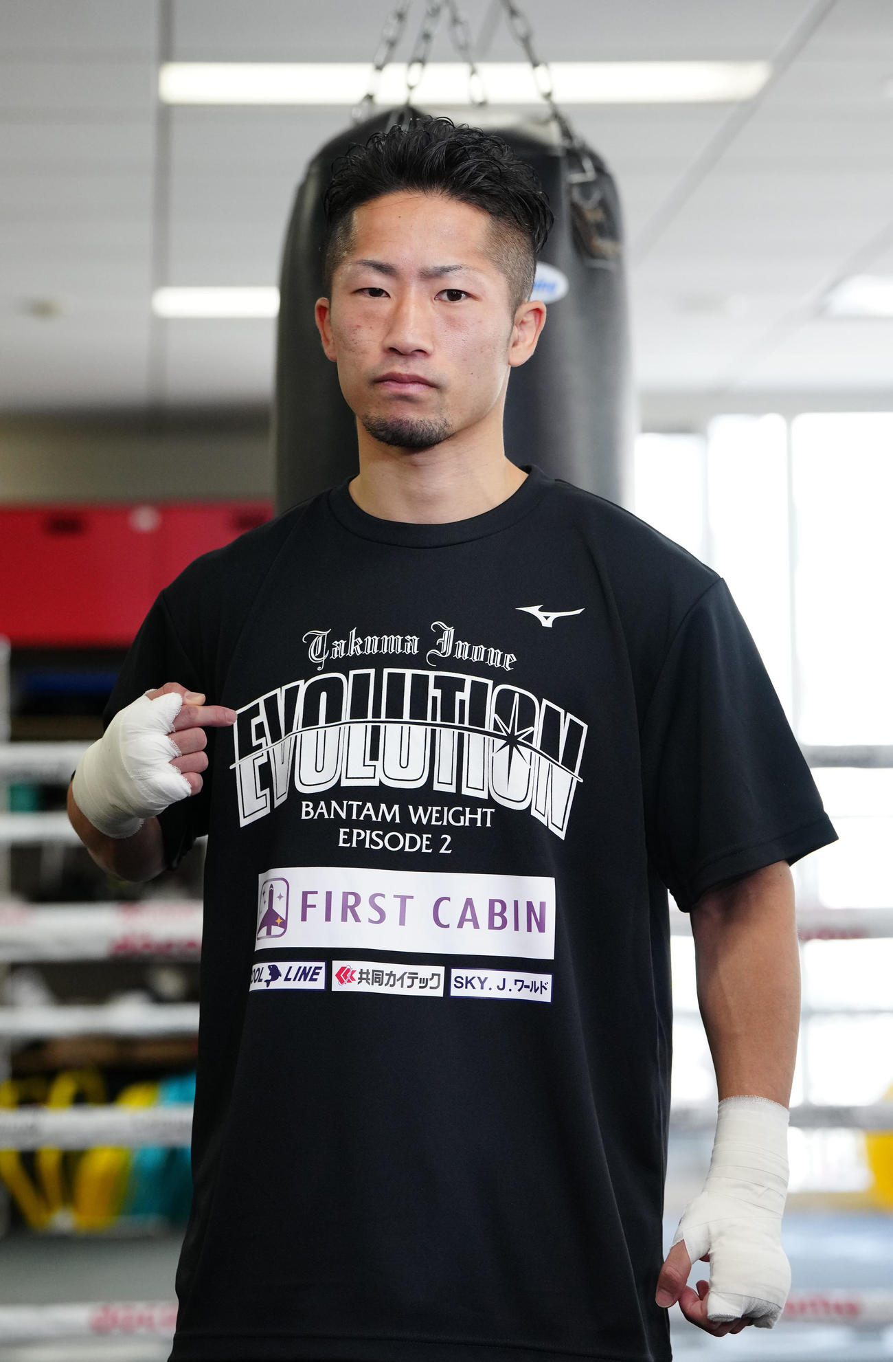 Tシャツの「EVOLUTION」の文字を指さす井上拓（撮影・江口和貴）