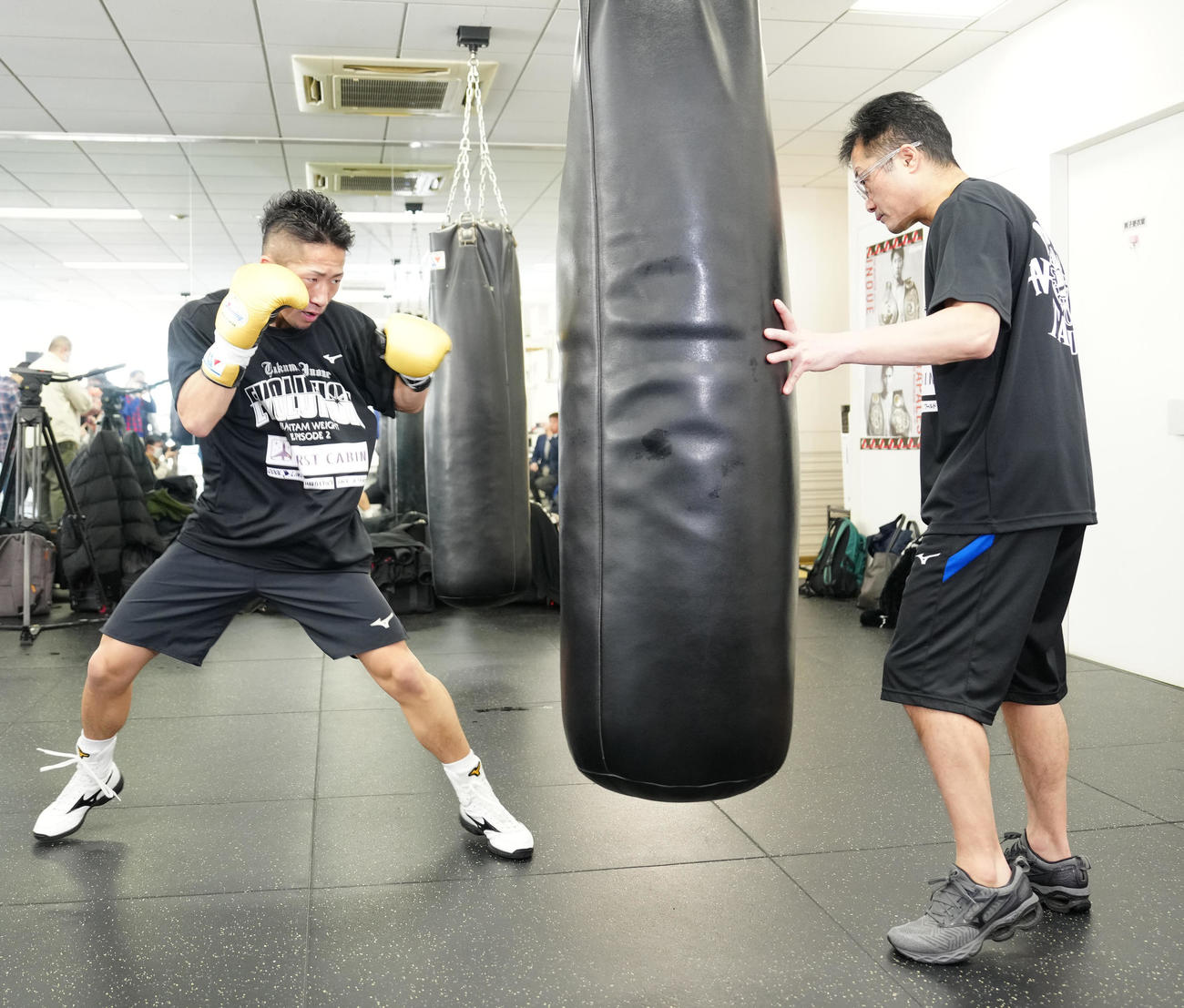 公開練習でサンドバッグにパンチを打ち込む井上拓（左）。右は父真吾トレーナー（撮影・江口和貴）