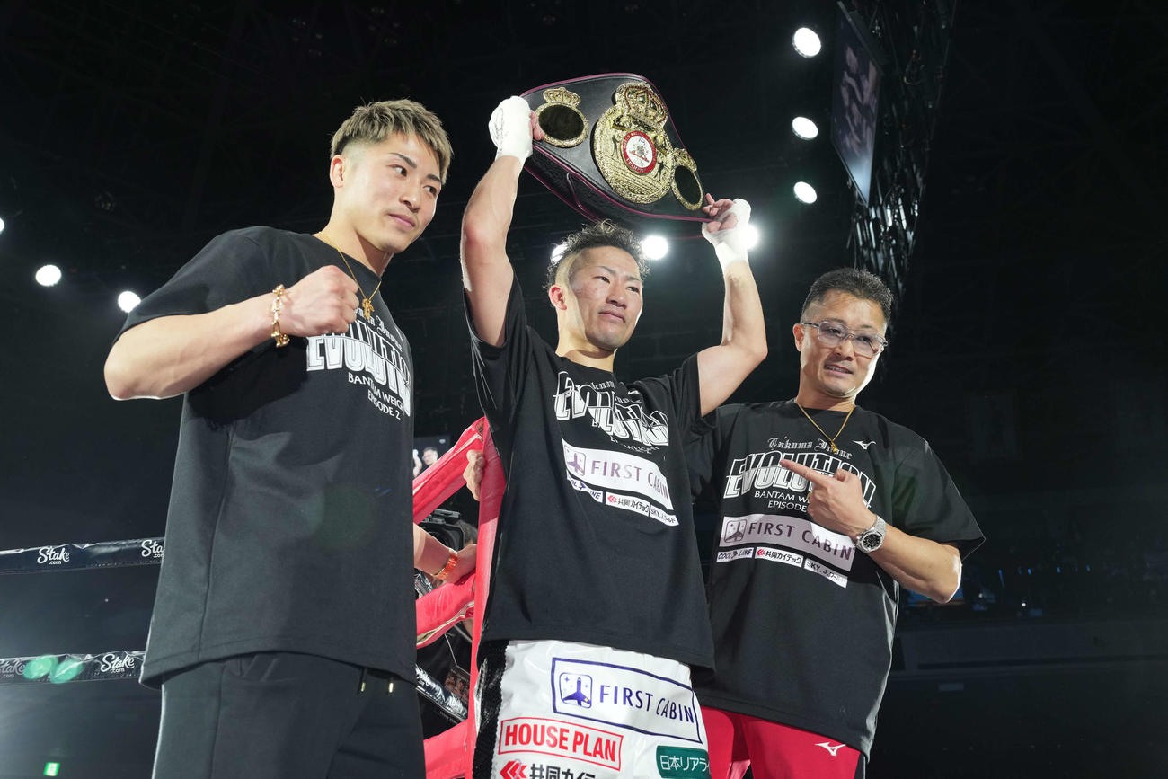 ベルトを掲げ、ポーズを決める井上拓（中央）。左は井上尚、右は父の真吾トレーナー（撮影・鈴木みどり）