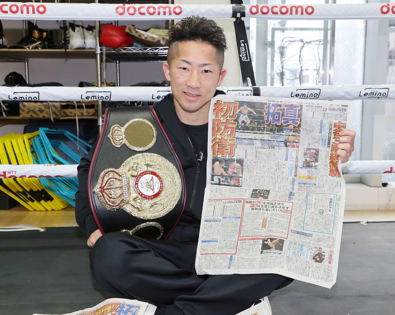 初防衛を報じる25日付日刊スポーツ東京最終版を手に笑顔を見せる井上（撮影・鈴木正人）