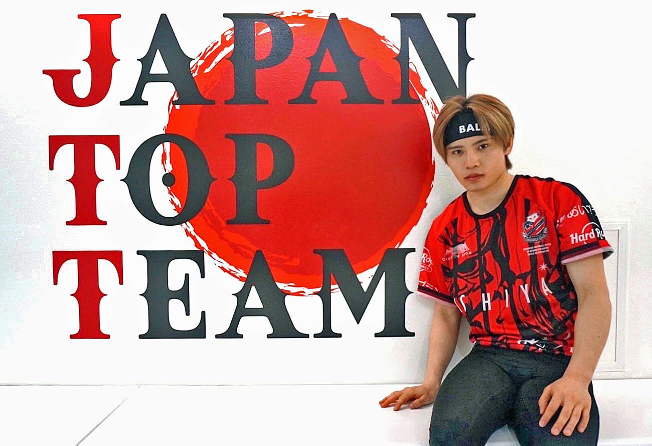 プロ2戦目に臨む鈴木は、“JAPAN TOP TEAM”のロゴの前でポーズ（提供写真）