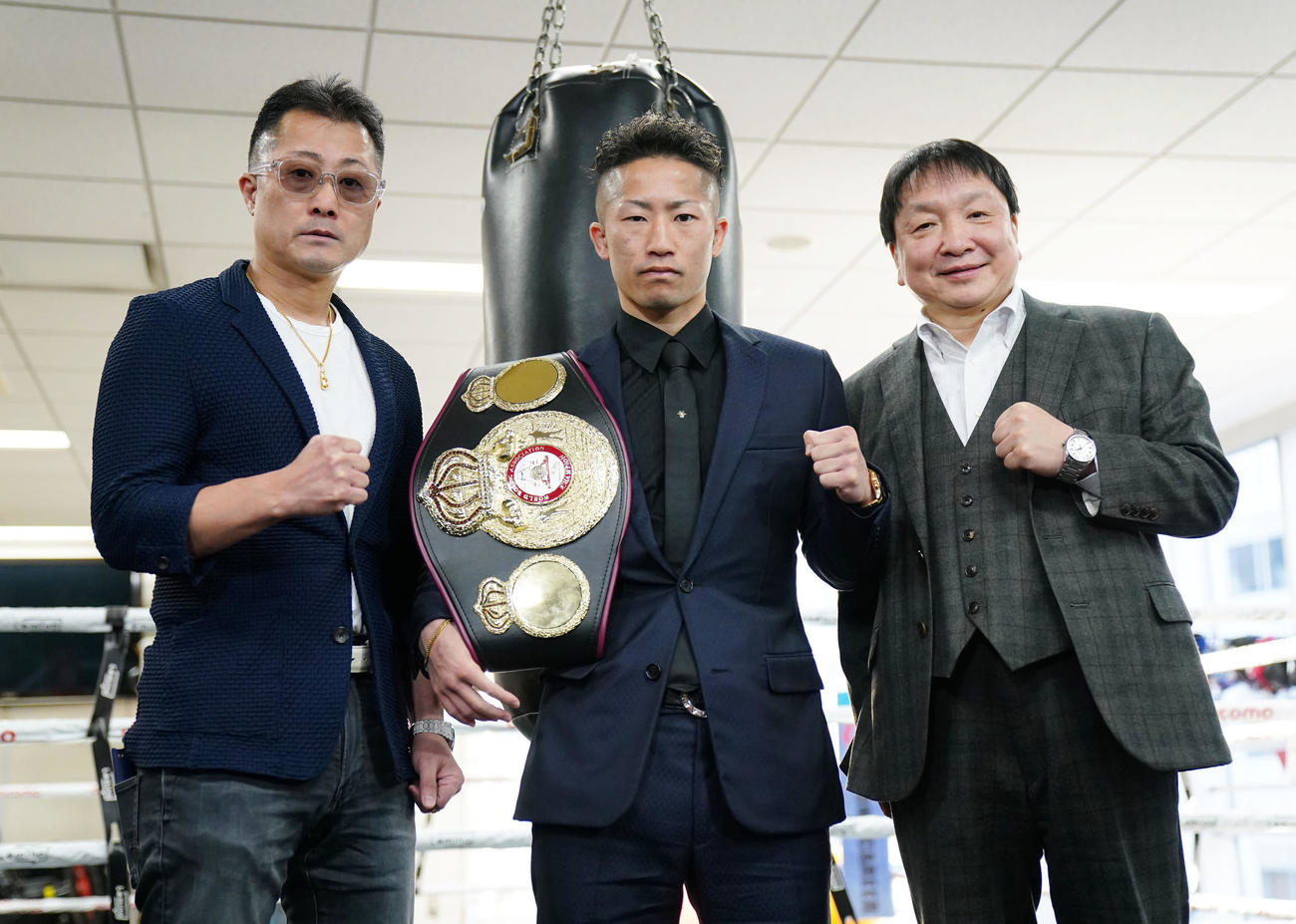 ベルトを肩にかけてポーズを決める井上拓。左は井上トレーナー、右は大橋会長（撮影・横山健太）