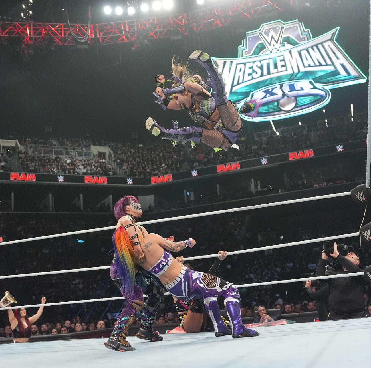 アスカ（下左）が抑えたティーガン・ノックス（下右に向け、インセインエルボーを狙うカイリ・セイン（C）WWE