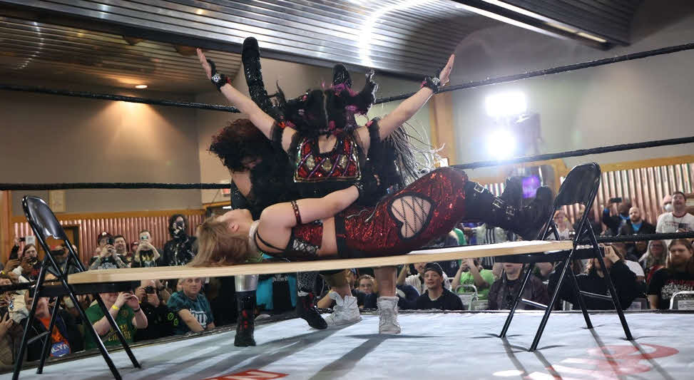 東京女子プロレス　テーブルの上に横たわる愛野ユキに、合体雪崩式パワーボムで落とされる伊藤麻希（東京女子プロレス提供）