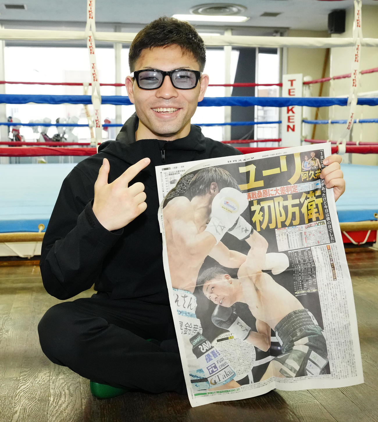 初防衛から一夜明け、本紙を手にポーズを決めるユーリ阿久井（撮影・江口和貴）