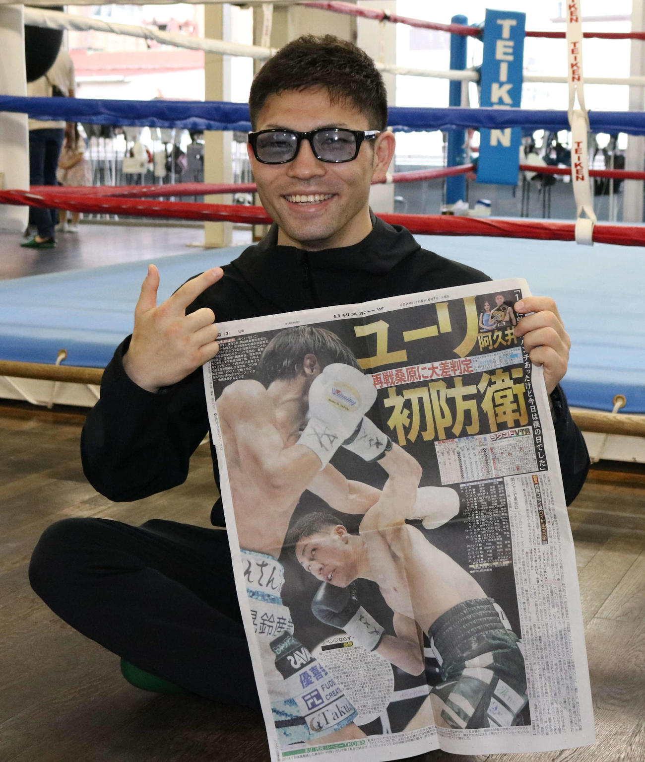 初防衛から一夜明け、本紙を手に笑顔を見せるユーリ阿久井（撮影・水谷京裕）