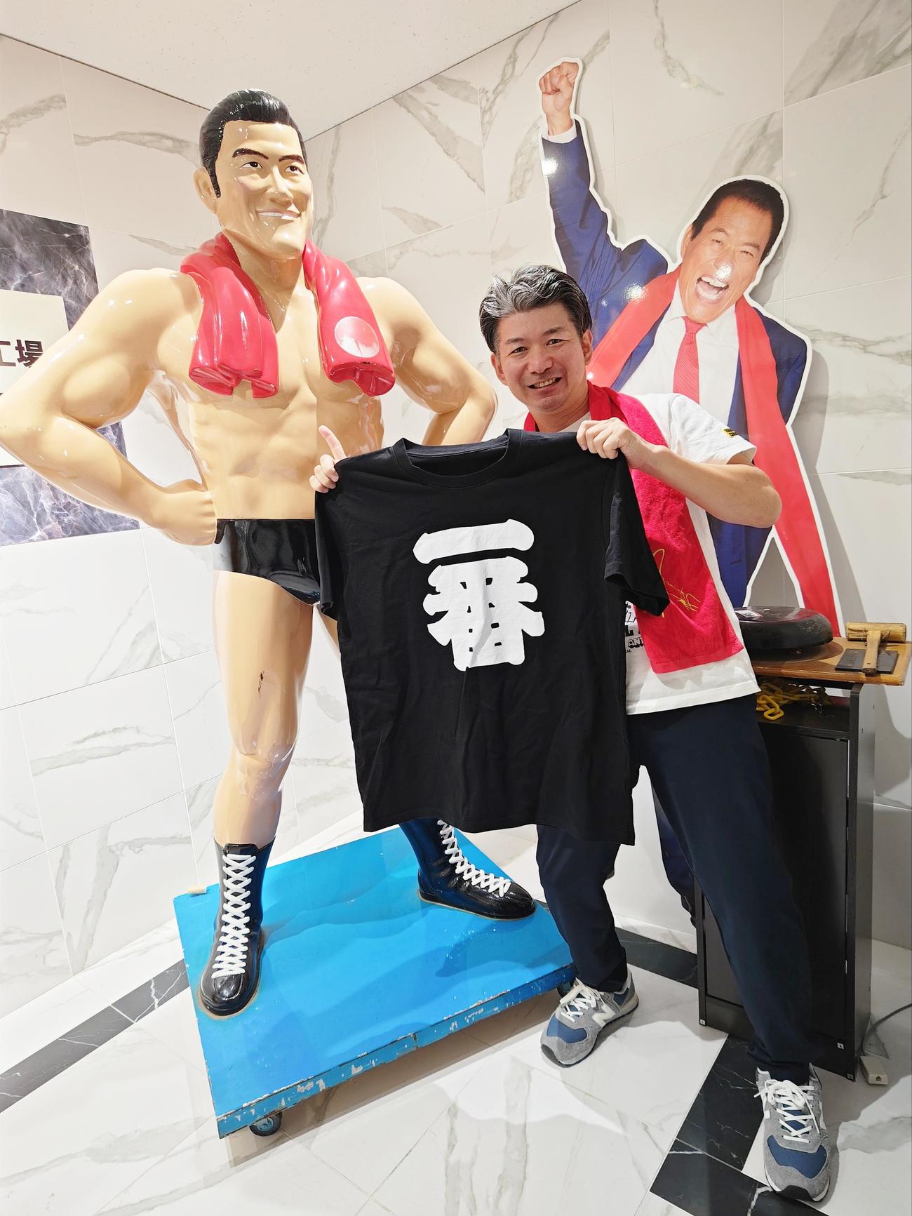 猪木さんのライバル、ハルク・ホーガンの着用した「一番」Tシャツを手にするIGFの宇田川強取締役