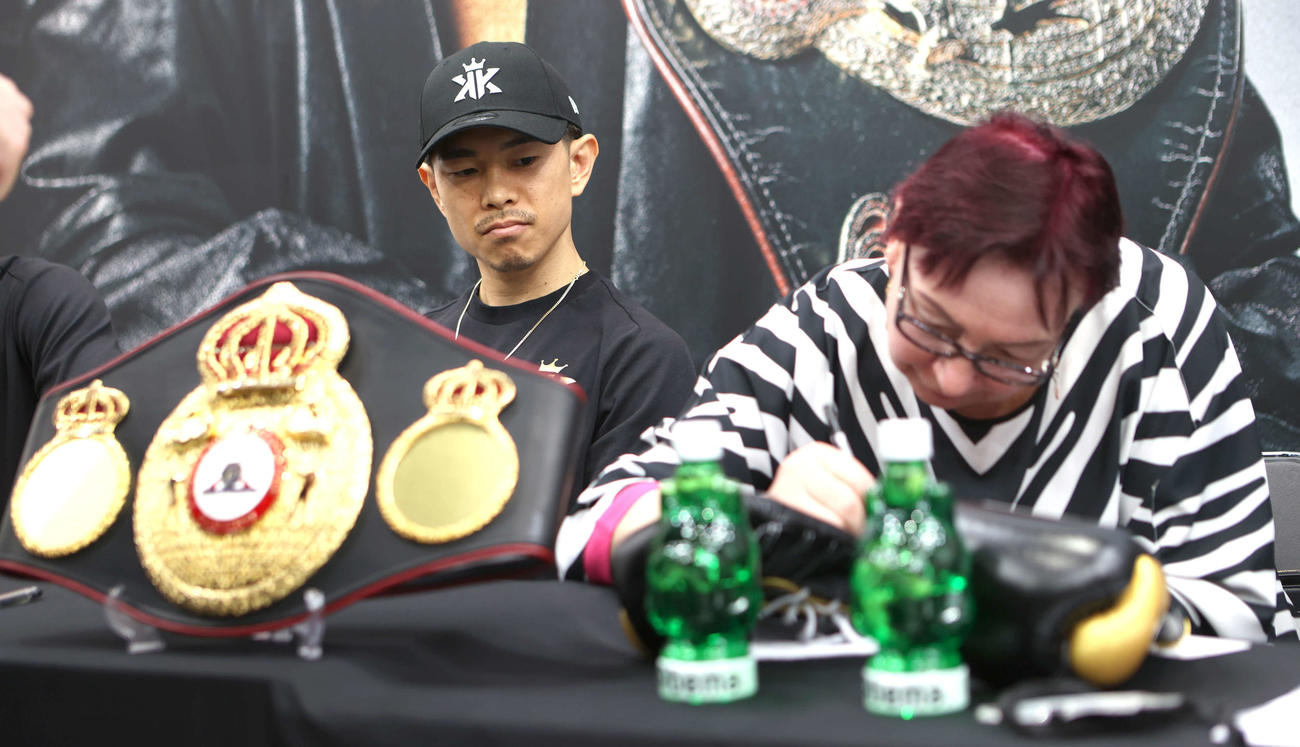 WBA、IBF世界スーパーフライ級王座統一戦の調印式でサインをする立会人のボリソヴァ氏を見詰める井岡（撮影・水谷安孝）