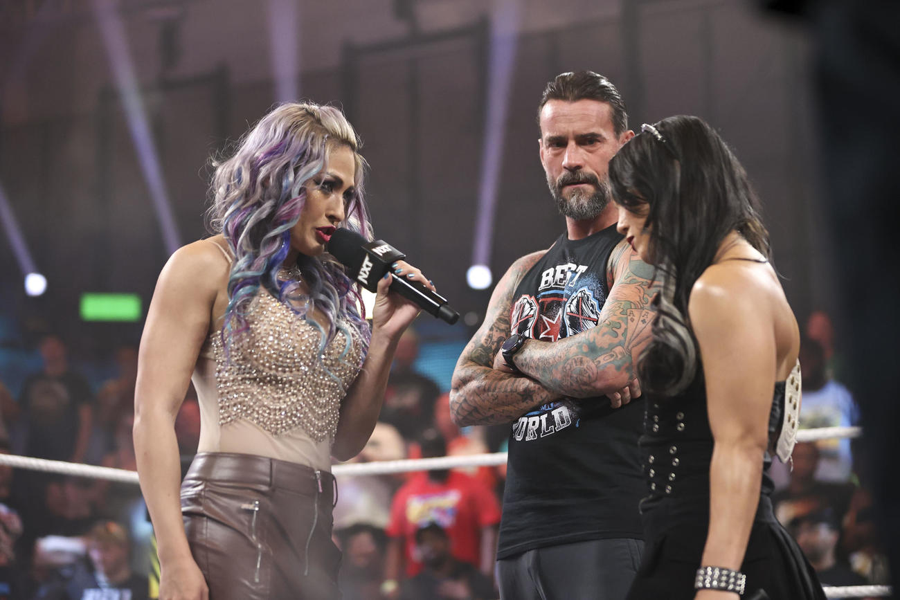 CMパンク（中央）を挟み、NXT女子王者ロクサーヌ・ペレス（右端）とにらみ合うジュリア（C）WWE