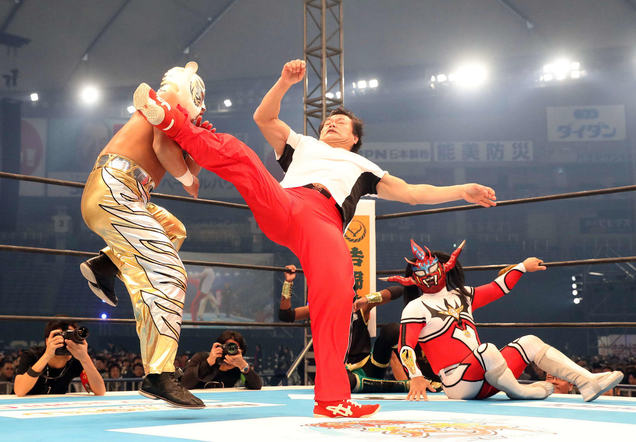 タイガーマスク（左）に後ろ回し蹴りを見舞う小林邦昭さん（中央）。右は獣神サンダー・ライガー（2017年1月撮影）