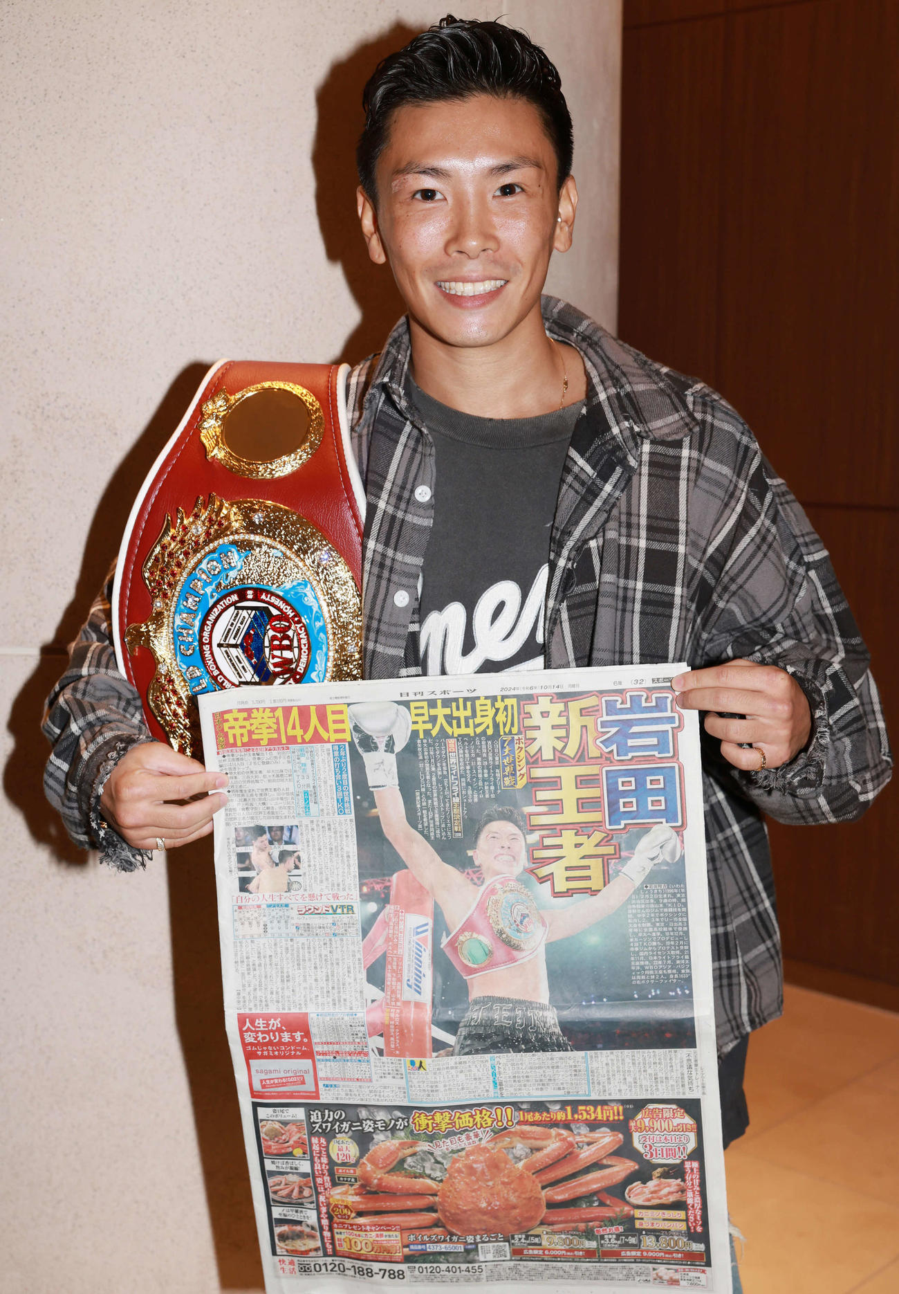 日刊スポーツを手にするWBO世界ライトフライ級王者の岩田（撮影・野上伸悟）