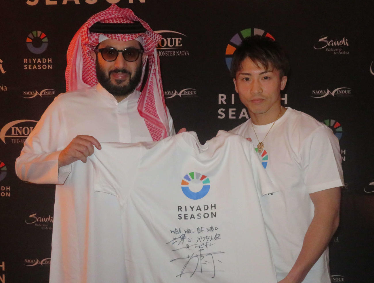 直筆サインを入れたリヤド・シーズンのロゴTシャツをサウジアラビア総合娯楽庁トゥルキ・アラルシク長官（左）に手渡す井上尚弥