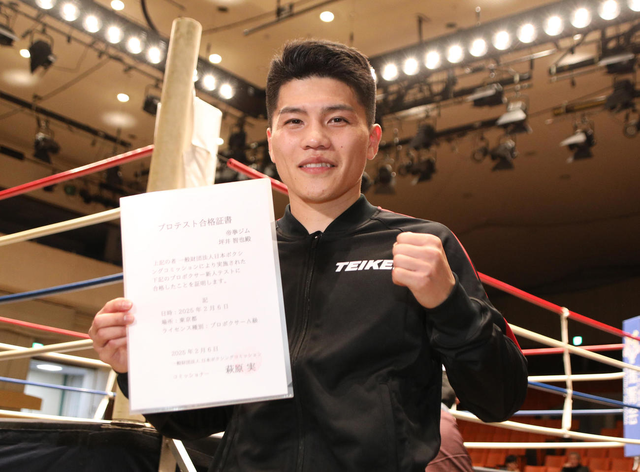 プロテスト試験に合格し合格証書を手にガッツポーズする坪井（撮影・中島郁夫）