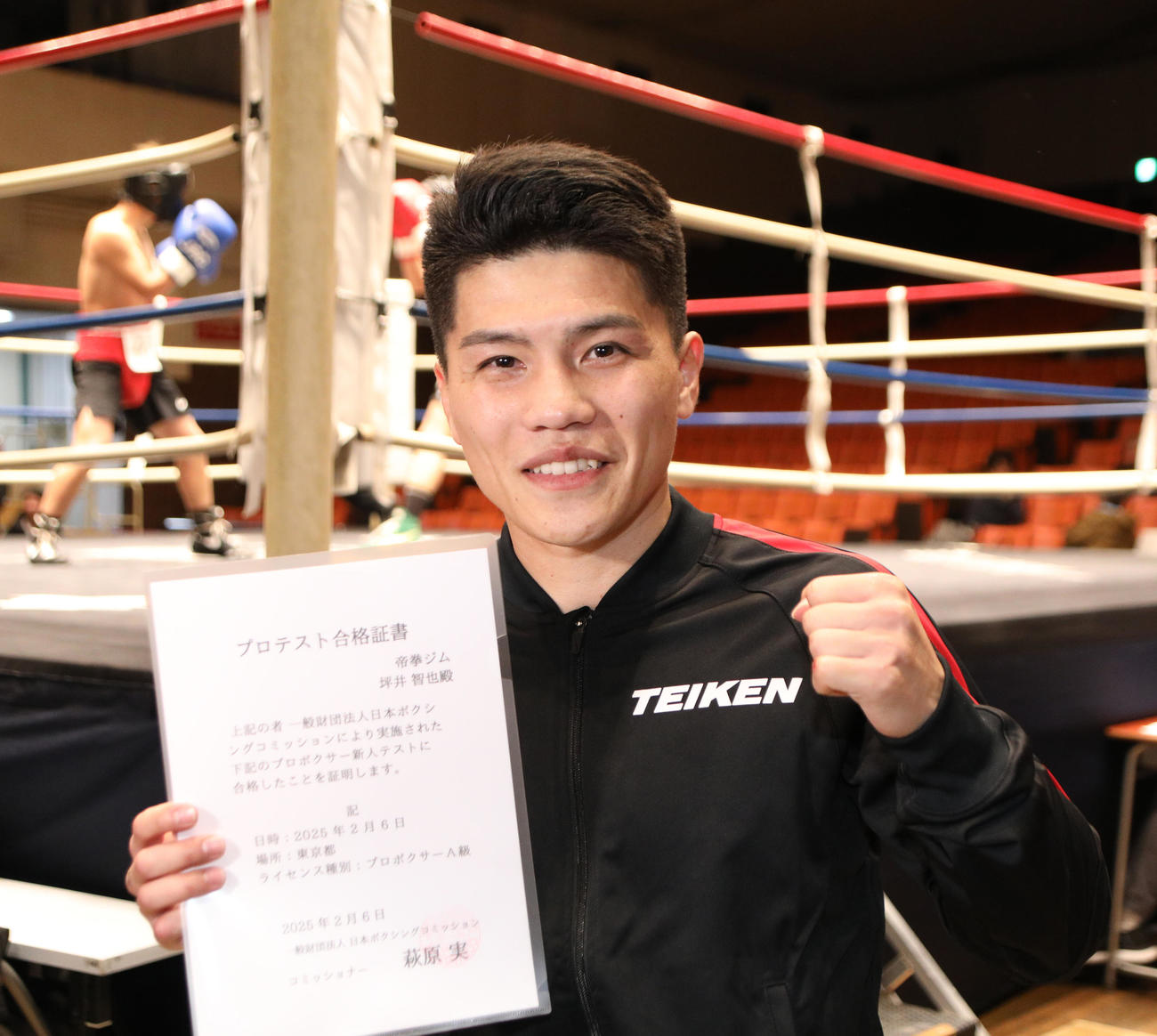 プロテスト試験に合格し合格証書を手にガッツポーズする坪井（撮影・中島郁夫）
