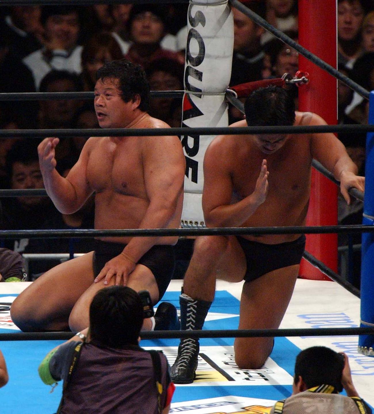 敗戦にぼう然とする藤波辰爾（左）の横で神に祈りを捧げる西村修＝03年1月4日