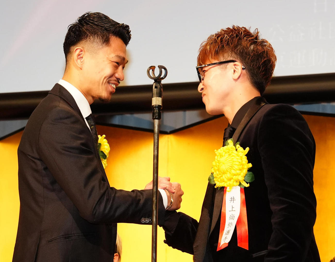 年間表彰式での壇上で握手を交わす井上尚（右）と中谷（撮影・江口和貴）