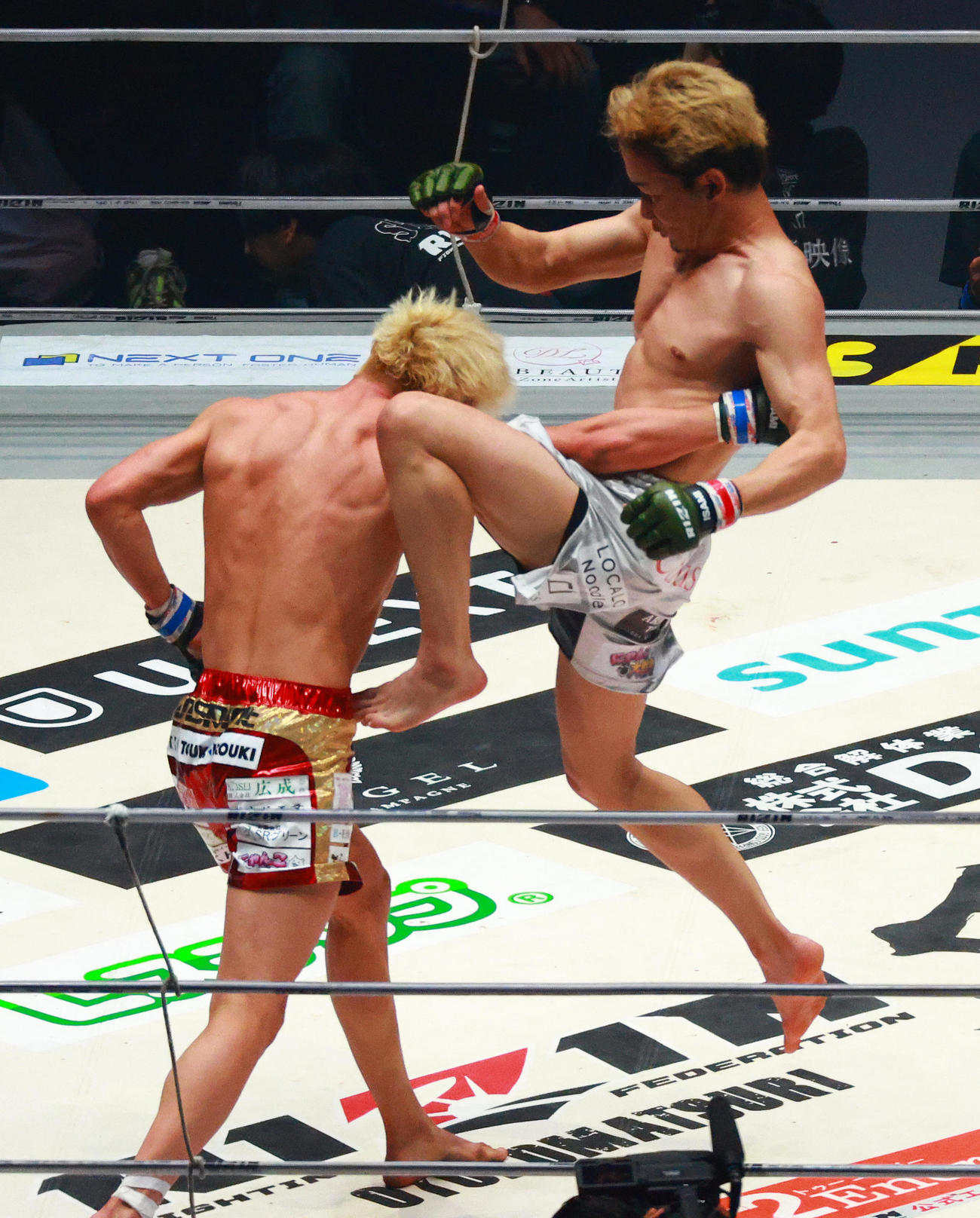 鈴木（左）にジャンピングニーキックを浴びせる朝倉（撮影・中島郁夫）