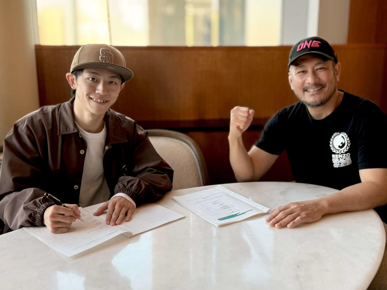 ONEの契約書にサインする吉成名高（左）とONEのチャトリ・シットヨートンCEO（C）ONE Championship