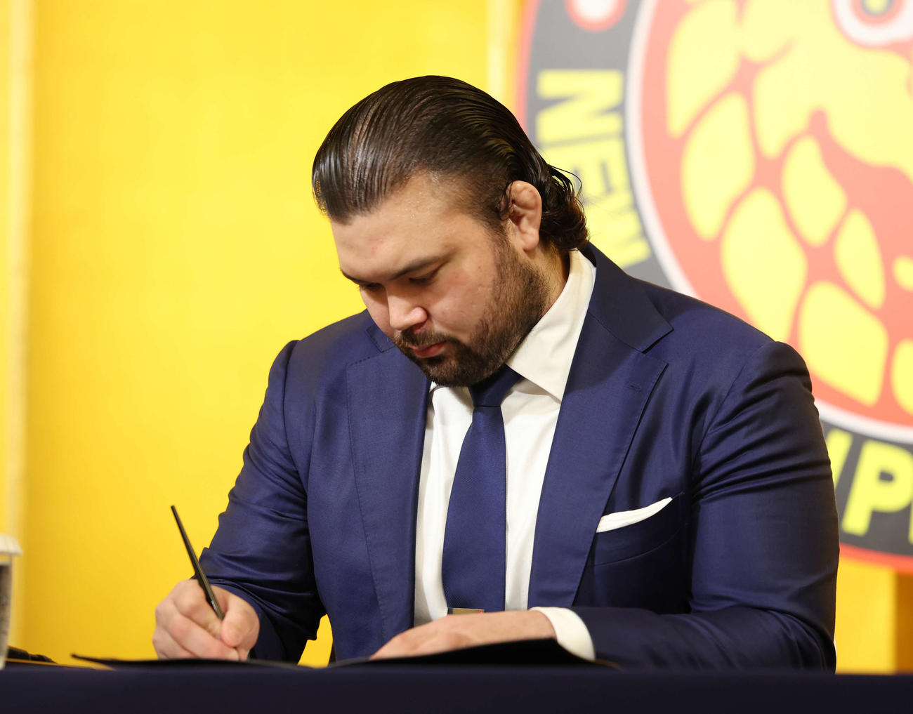 新日本プロレス入団会見で契約書にサインをするウルフ・アロン（撮影・増田悦実）