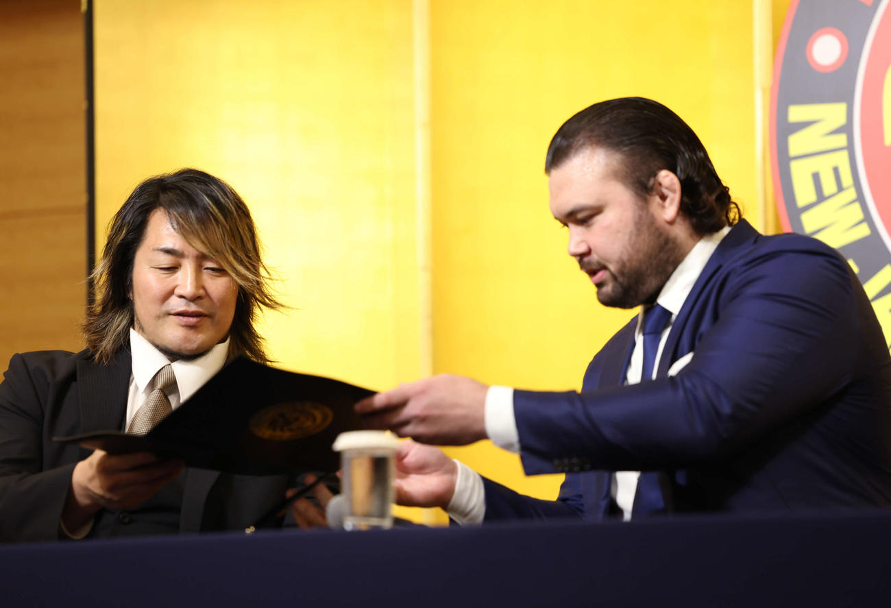 新日本プロレス入団会見で契約書を新日本の棚橋社長（左）に手渡すウルフ・アロン（撮影・増田悦実）