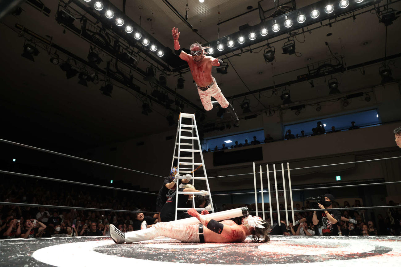 脚立の上から蛍光灯の束を抱いたデスペラードの上にダイブする葛西純（C）新日本プロレス