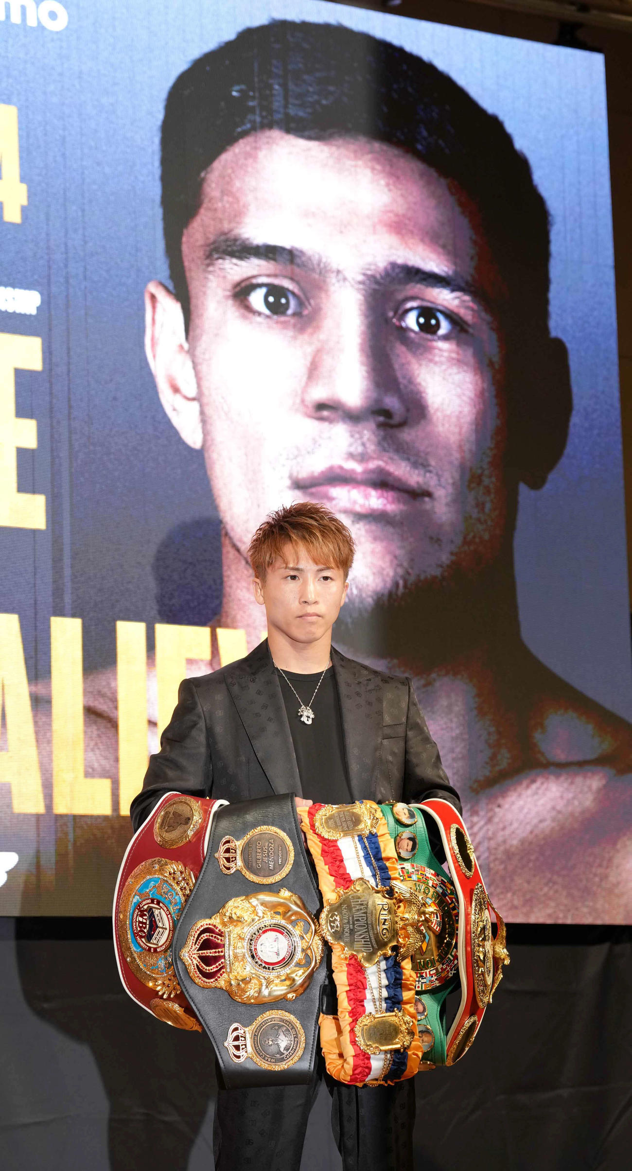 トリプル世界戦の開催発表記者会見で挑戦者のアフマダリエフの写真を背に記念撮影に臨む4団体統一王者の井上尚（撮影・小沢裕）