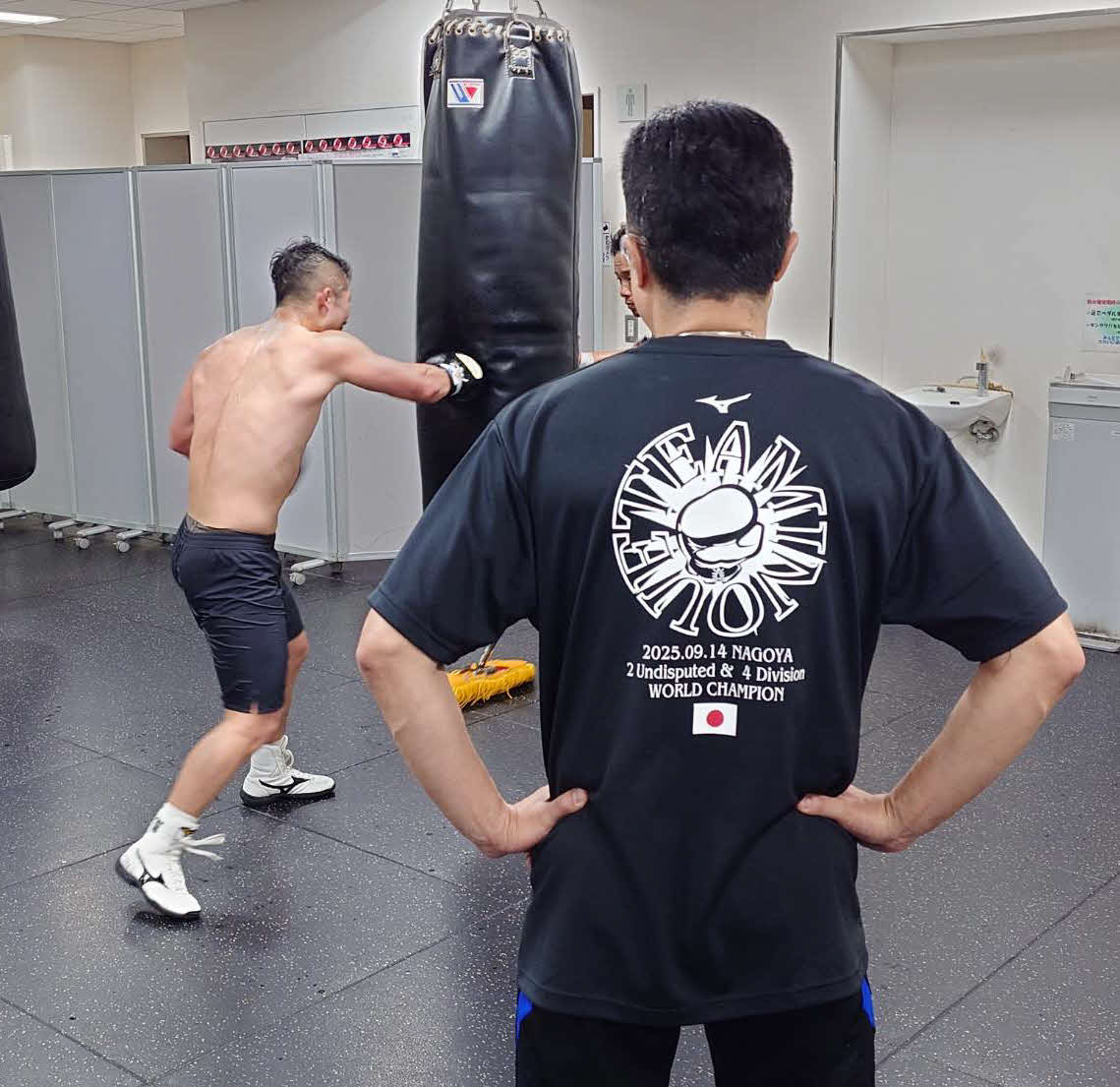 父真吾トレーナー（手前）がチェックする中、サンドバッグ打ちする井上拓真（大橋ジム提供）