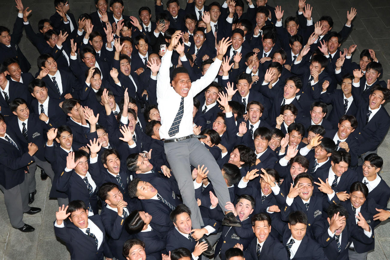 日本ハム2位の大阪学院大エドポロ・ケイン（中）は野球部員に胴上げで祝福される（撮影・西尾就之）