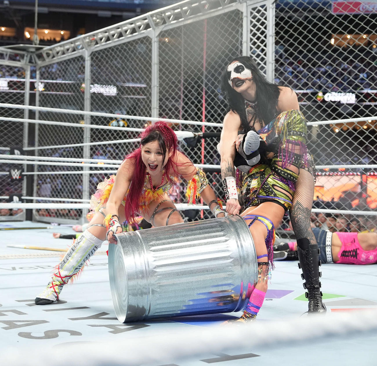 リア・リプリー（右端）と敵チームのカイリ・セイン（中央）とトラッシュ缶に入れるイヨ・スカイ（C）WWE
