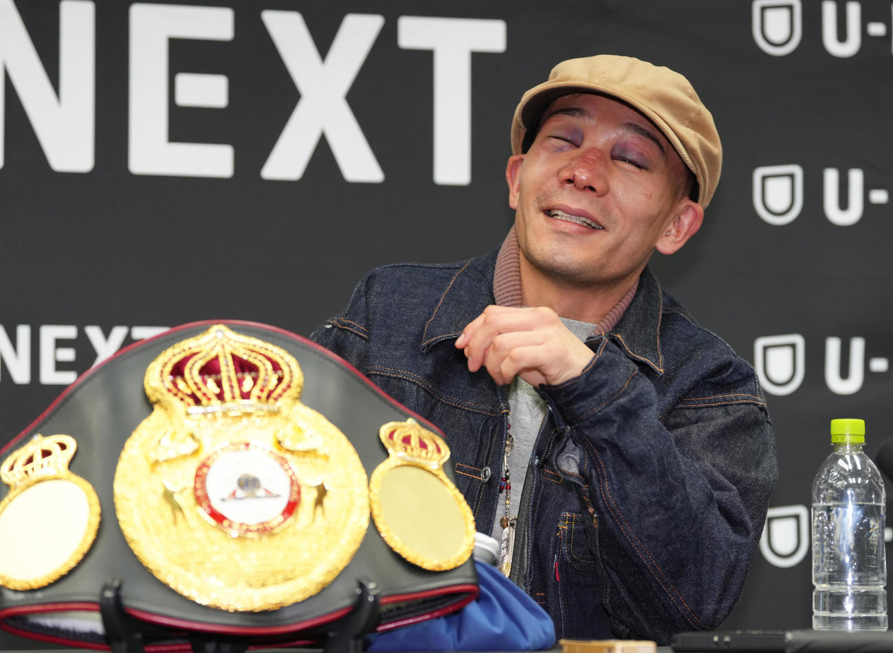 一夜明け会見中、笑顔を見せながら痛がる堤（撮影・足立雅史）