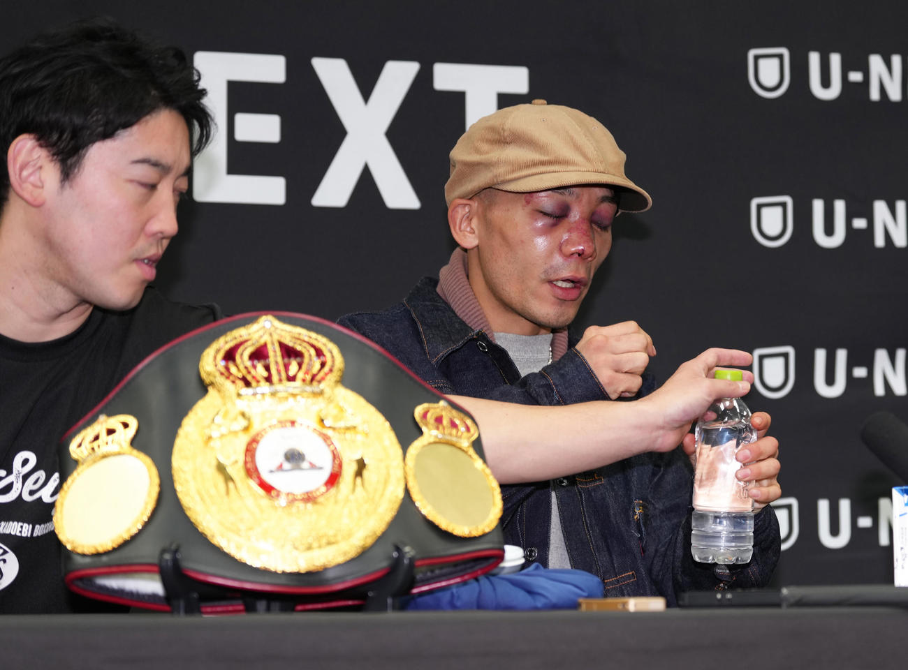 一夜明け、会見中、痛み止め薬を服用する堤（右）。左は石原トレーナー（撮影・足立雅史）