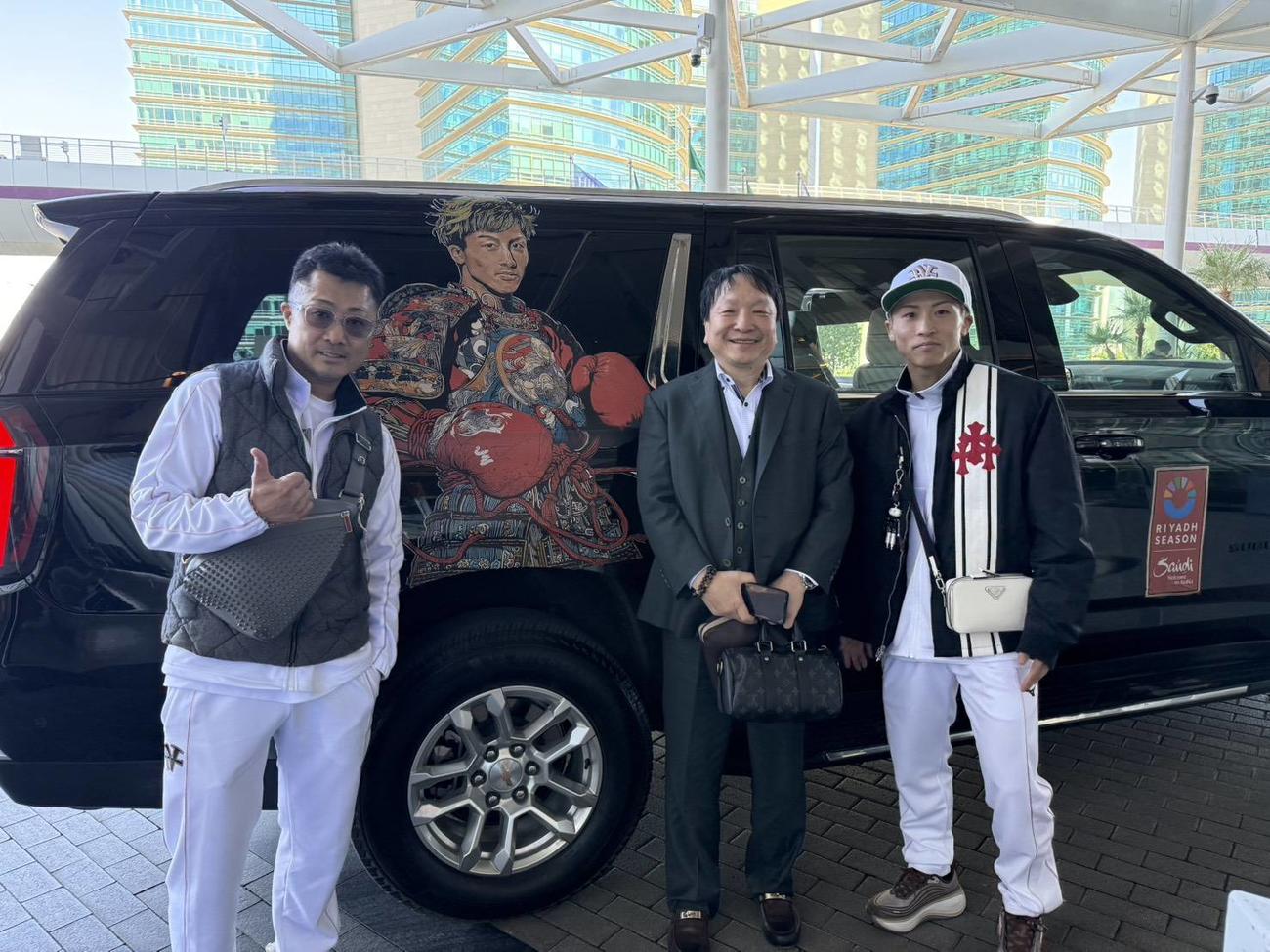 自身のイラストがプリントされた専用車の出迎えを歓迎する井上尚弥（右端）、大橋秀行会長（中央）、井上の父真吾トレーナー（大橋ジム提供）