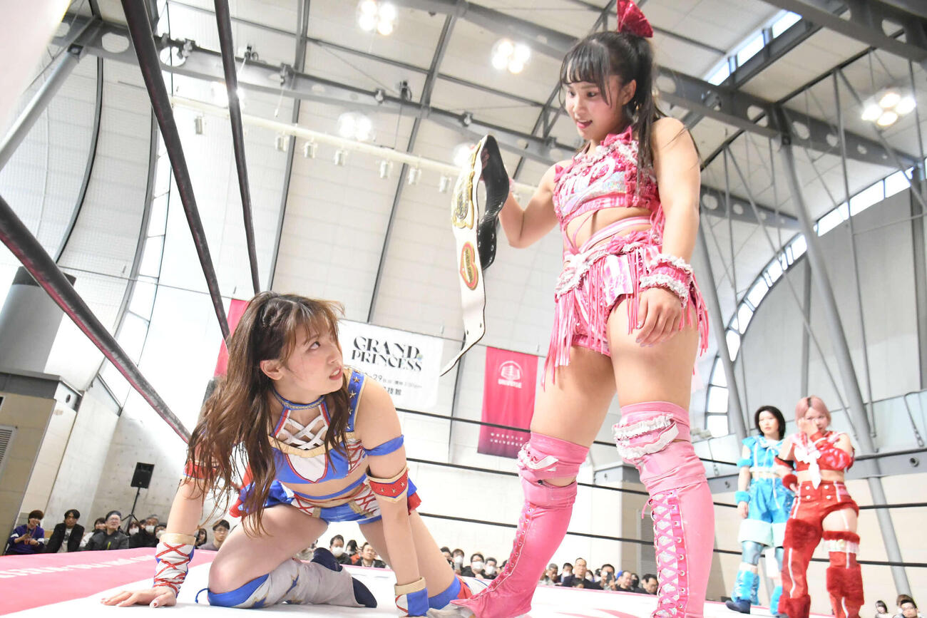 ベルトをかかげて荒井優希を見下ろす渡辺未詩（C）東京女子プロレス