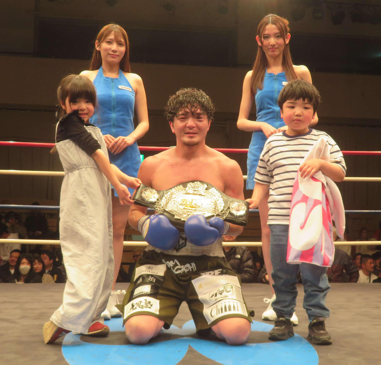 2人の子供、ラウンドガールとともに日本スーパーウエルター級王座ベルトを掲げる同級王者左右田泰臣（前列中央）