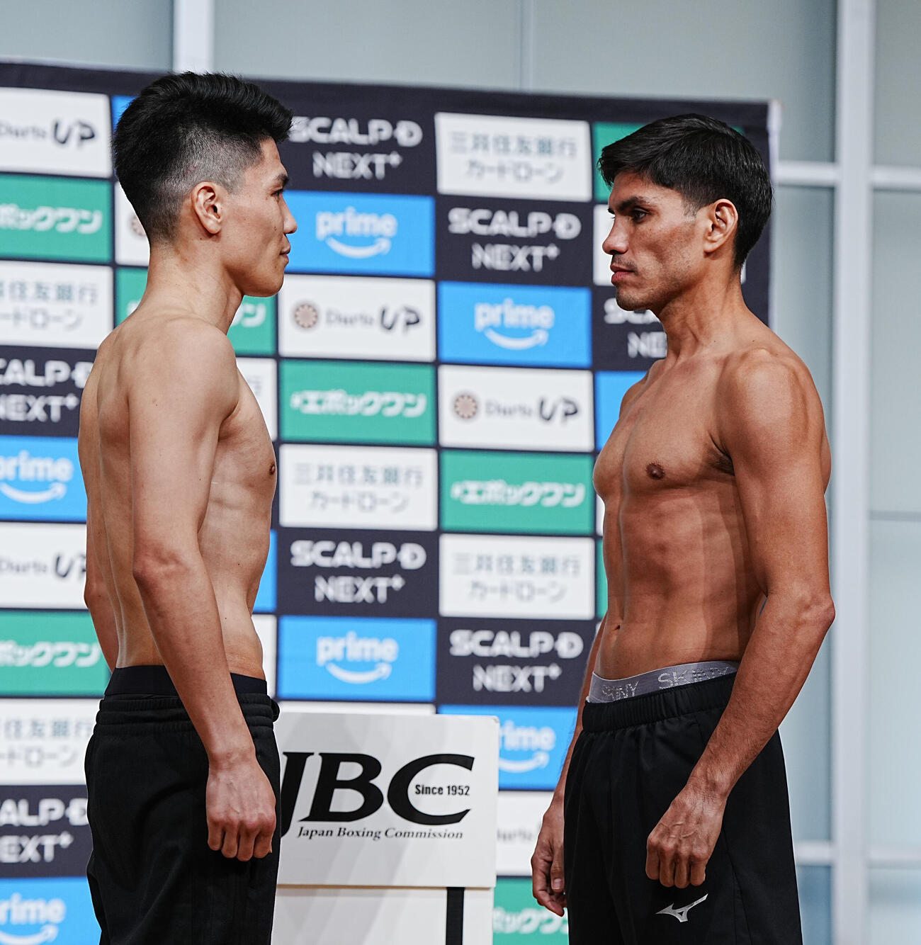 WBC世界スーパーフライ級10回戦の計量をパスしフェイスオフする坪井（左）と対戦相手のゲバラ（撮影・小沢裕）