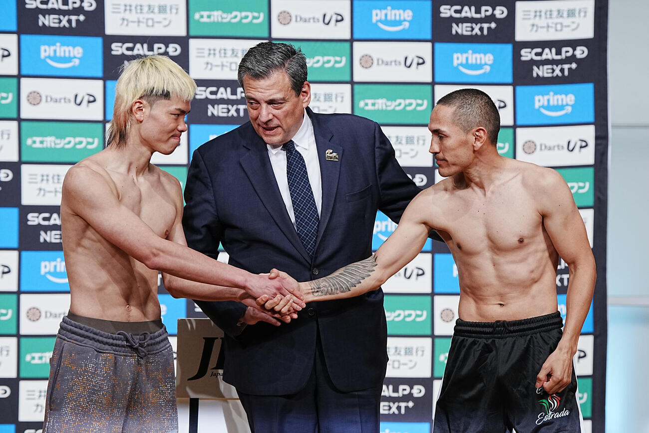 WBC世界バンタム級挑戦者決定戦の計量をパスし立会人のスライマンWBC会長との記念撮影を終えた那須川（左）は対戦相手のエストラダ（右）とがっちり握手する＝2026年4月10日