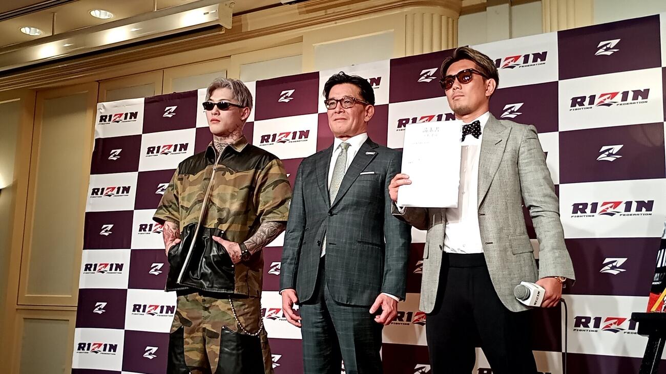 壇上で平本蓮（左）、皇治（右）と並ぶ榊原信行CEO