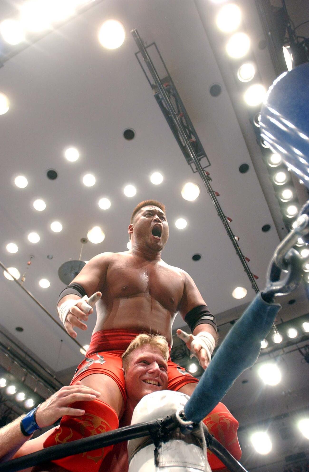2003年11月、ポストで勝利の雄たけびを上げる天山広吉は、ジョシュ・バーネット（下）から肩車され驚きの表情を見せた