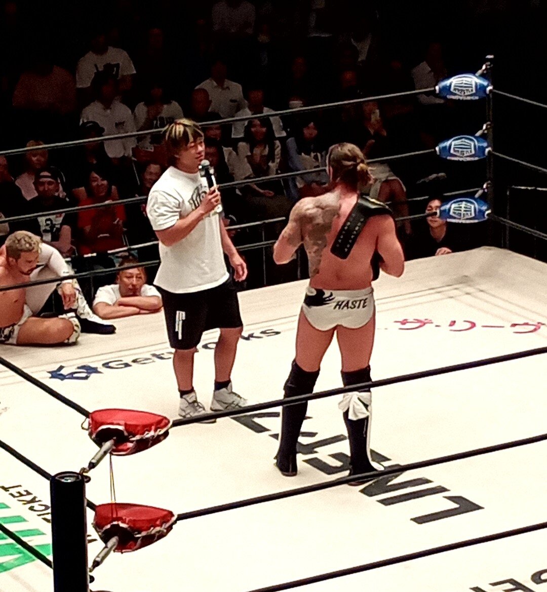 遠藤哲哉（中央）がシェイン・ヘイストへ挑戦を直訴している間、ダメージを負ったKENTA（左）が通訳をするハメに