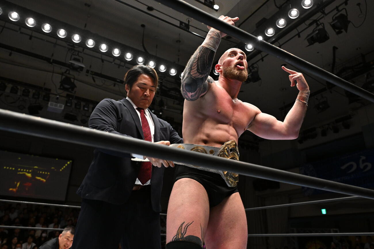 棚橋弘至社長にベルトを巻いてもらいながら、ファンにも中指を立てるゲイブ・キッド（C）新日本プロレス