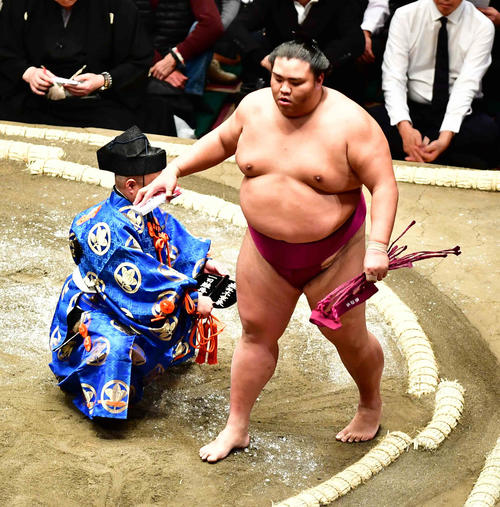 初日から3連勝の御嶽海は懸賞を手にする(撮影・小沢裕)