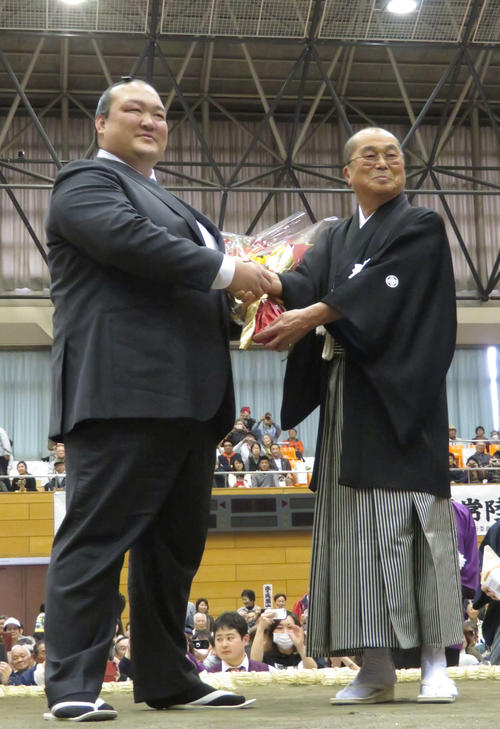 地元茨城県で行われた巡業で、常陸大宮市の三次市長（右）から花束を受け取った荒磯親方