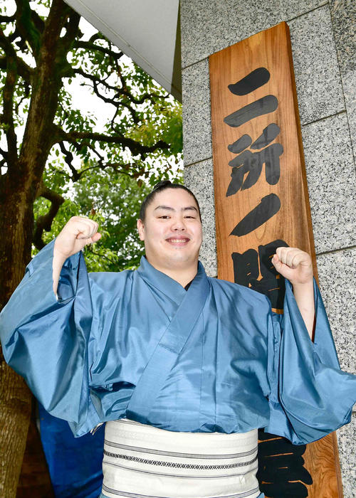来場所での十両昇進が決まった一山本は二所ノ関部屋の看板の前でガッツポーズ（撮影・小沢裕）　