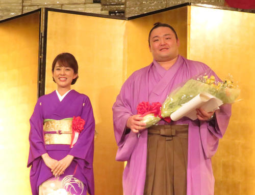 富山県人会で、同じ特別ゲストの演歌歌手丘みどり（左）から花束を受け取り、笑顔を見せる朝乃山