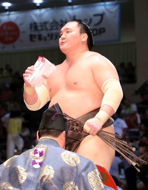 懸賞金の束を手に土俵を引き揚げる白鵬（撮影・鈴木正人）