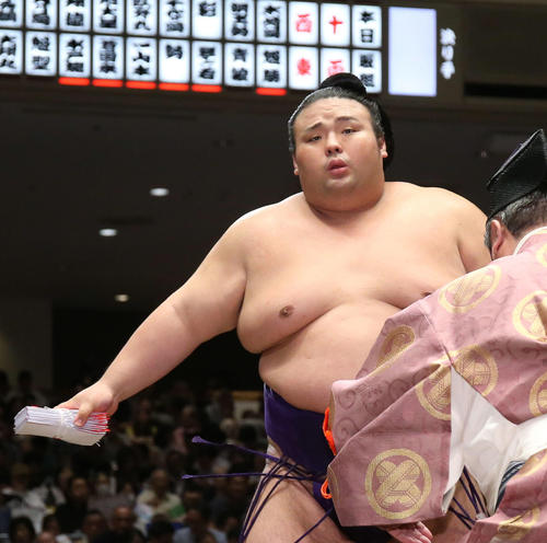 懸賞金の束を手に土俵から引き揚げる貴景勝（撮影・河田真司）