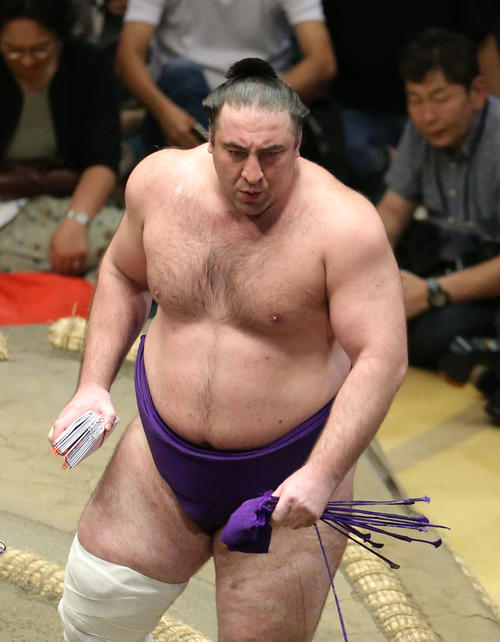 懸賞金の束を手に土俵から引き揚げる栃ノ心（撮影・河田真司）