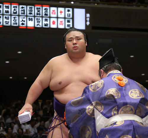 懸賞金の束を手に土俵から引き揚げる貴景勝（撮影・河田真司）